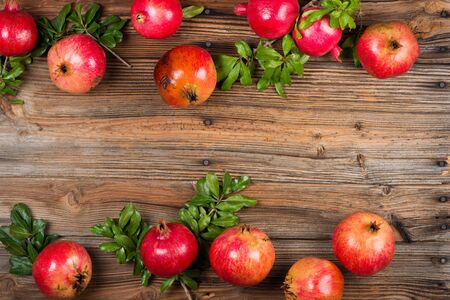 Organic pomegranate fruits with branches of  pomegranate tree on dark rustic wooden table. Top view, copy space for text.の写真素材