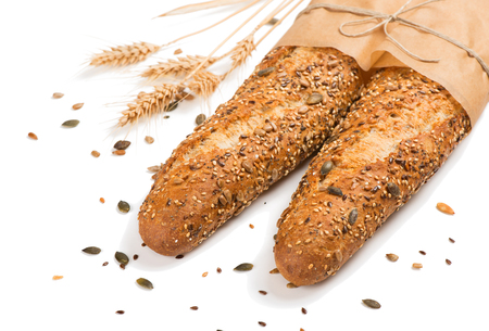   Two baguettes baked bread in paper with different seeds ( pumpkin, poppy, flax, sunflower, sesame, millet ) decorated with wheat ears isolated on white background. の写真素材