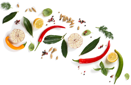 Top view of composition of herbs and spices ( pepper, basil, cardamom, bay leaf, garlic, lemon, dill and chilli ) isolated on white background. の写真素材