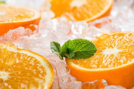 Sliced fresh oranges on ice cubes decorated with leaves of mint. Selective focus on the mint.の写真素材