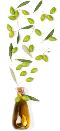   Falling green olive fruits in a glass bottle with olive oil isolated on white background.   の写真素材
