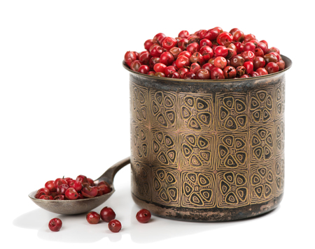 Pink or red, peppercorns in a bronze bowl and in the spoon isolated on white background.  の写真素材