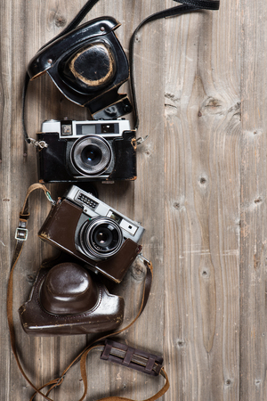 Two old cameras and cases on a rustic wooden background with copy space, top view.の写真素材