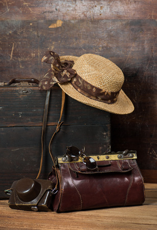 Old wooden suitcase, women's straw hat, retro camera and travel bag on a dark grunge background. The concept of travel.の写真素材