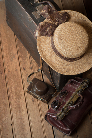 Top view of old wooden suitcase, women's wicker hat, retro camera and travel bag on a dark grunge background. The concept of travel.の写真素材