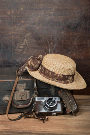 Travel concept with vintage suitcase, wicker hat and old camera a dark wooden grunge background with copy space. の写真素材