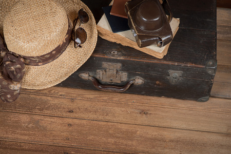Top view of vintage suitcase, wicker hat, old camera and book a dark wooden grunge background with copy space.  Travel concept.の写真素材