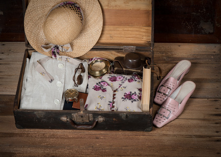 Anticipation of voyage. Women's clothes and accessories in old suitcase on wooden floor. の写真素材