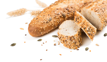 Baguettes bread whole and sliced with different seeds ( pumpkin, poppy, flax, sunflower, sesame, millet ) decorated with wheat ears isolated on white background.  Selective focus.の写真素材