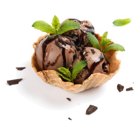 Chocolate ice cream balls sprinkled with chocolate pieces and topping chocolate sauce in a waffle basket decorated with mint isolated on white background.の写真素材
