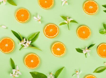 Fruit pattern of orange slices and blossom with leaves on green background. Top view. Flat lay.の写真素材