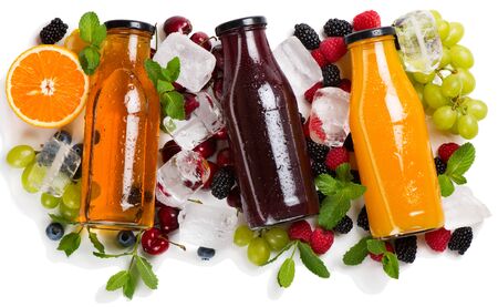 Three glass bottles wits cold fruit and berry juices with ice.の写真素材