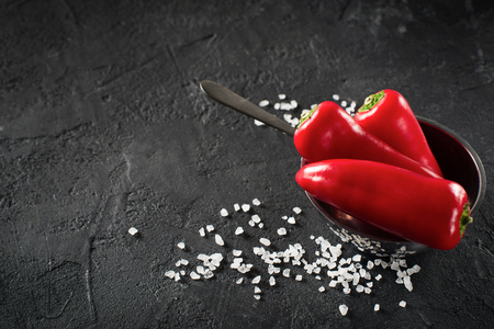 Some mini peppers and salt over black backgroundの写真素材