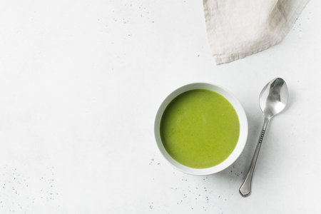 Green vegetable soup on white background minimalism, copy space, top viewの写真素材