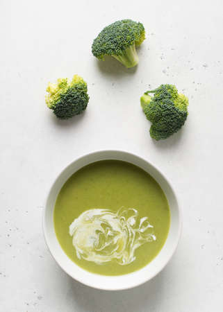 Green vegetable broccoli soup on white background minimalism, copy space, top view, vertical