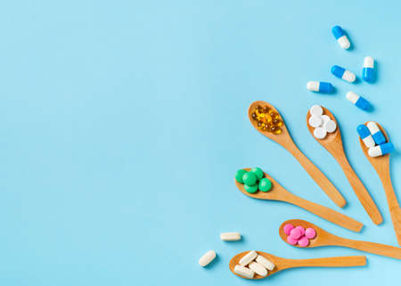 Set of colorful pills and tablets in spoon on blue background. Copy space, top viewの写真素材