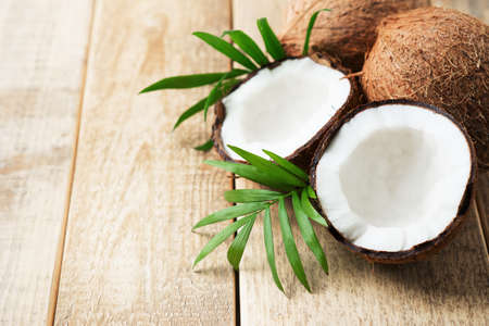 Fresh coconut with leaves on wooden background, copy space