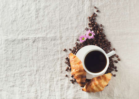 Breakfast concept with cup of coffee, croissants, flower and coffee beans on table, morning, copy space, top viewの写真素材
