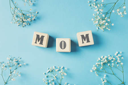 Mothers day concept, greeting card with word mom on toy cubes and flowers on blueの写真素材