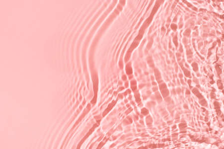 Transparent and clean pink water background with sunlight reflection, top view