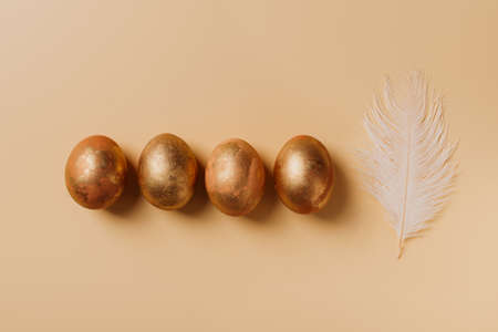Golden egg with feather, easter concept, flat lay, on yellow background, copy space, top viewの写真素材