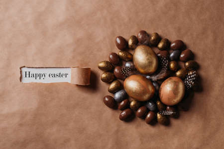 Easter concept with golden eggs and candy sweet on yellow background and signature, copy space, top view, flat layの写真素材