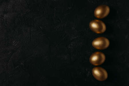Easter concept card with golden eggs and candy sweet frame falt lay on black background, copy space, top viewの写真素材