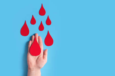 World hemophilia day concept with red blood drop simbol and hands on blue backgroundの写真素材