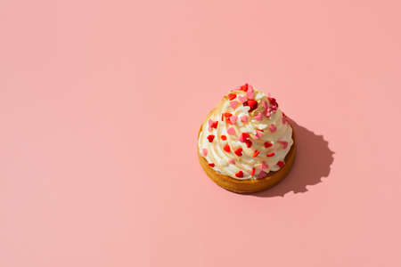 Cupcake with cream and decorative hearts on mothers day or valentines on pink background, copy space, minimalism, creativeの写真素材