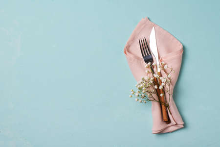 Tableware setting with fork, knife, napkin and flower on blue background,の写真素材