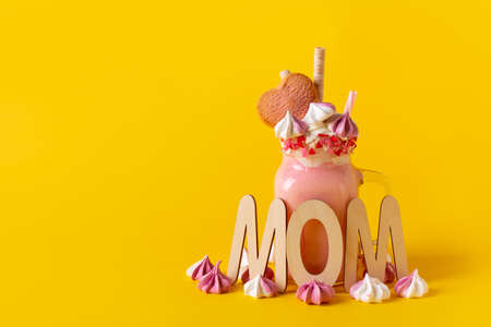 Pink milkshake with cream, marshmallow candy hearts on pink background