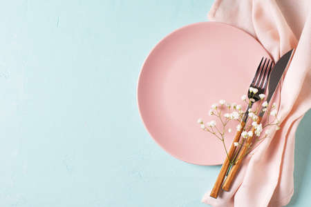 Tableware setting with fork, knife, napkin and flower on blue background, spring serving, top view, copy space, flat layの写真素材