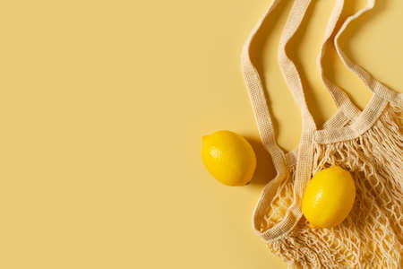 Zero waste concept with string bag, mesh bag, grosery bag with lemon on yellow background, flat lay,...
