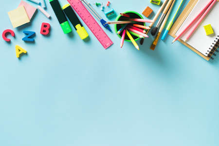 School supplies color background flat lay on blue background, back to school concept, copy space