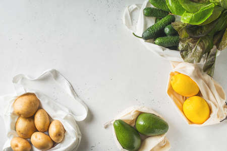 Zero waste concept. Textile ecologiical shopping bags with fruits and vegetables on white background, copy space, top viewの写真素材