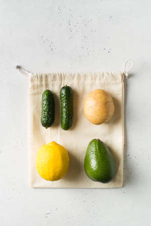 Zero waste concept. Textile ecologiical shopping bags with fruits and vegetables on white...