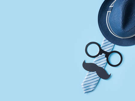 Fathers day concept with hat, glasses and tie on blue background, greeting card, copy space, top viewの写真素材
