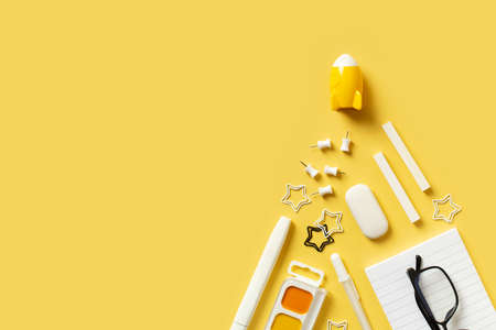 Back to school theme with white schools tools and rocket on yellow background flat lay, top view,...