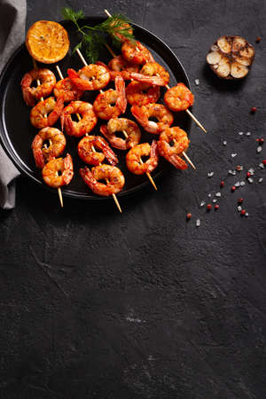 Grilled shrimp with garlic and lemon on black background, flat lay, top view, copy space, verticalの写真素材
