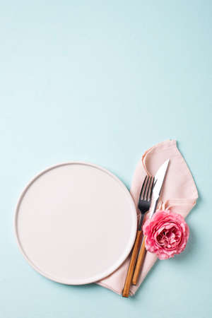 Tableware setting with fork, knife, napkin and flower on blue background,の写真素材