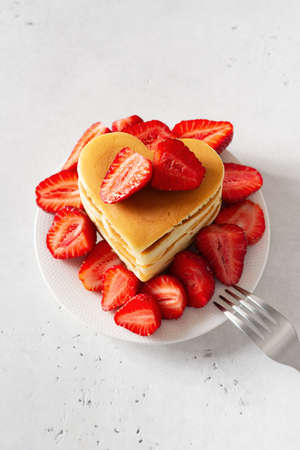 Stack of heart pancake with strawberry on white background, mothers and valentine day concept, top...