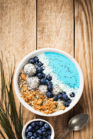 Blue smothie in bowl with granola and berries on white backgroundの写真素材