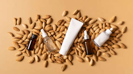 Essential almond oil and serum bottles nuts almonds with shell on beige or yellow background, top view and flat lay, mock upの写真素材