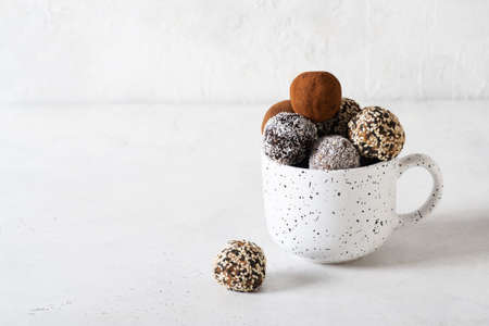 Carob energy balls with nuts, dates and coconut in cap, vegan and vegetarian sweet food, white...