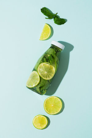 Refreshment water in bottle with lime, lemon and mint or mojito cocktail on blue background, copy space, verticalの写真素材