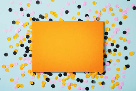 Halloween party concept with color confetty and orange paper note on blue background, empty space...