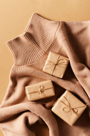 Eco friendly craft gift box with cozy sweater on brown background, top view, copy space, flat layの写真素材
