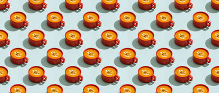 Autumn pumpkins soup in red orange bowl or cup on blue background, modern concept, seamless pattern, bannerの写真素材