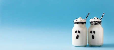 Funny white milkshake ghost cocktail on blue background, halloween concept, copy spaceの写真素材
