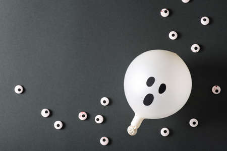 Balloons ghost with eyes on black background, halloween concept party, copy space, top view, flat layの写真素材